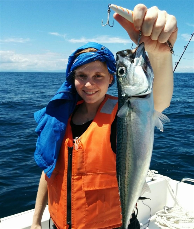 A smiling Kotori-maru guest holding a freshly caught mackerel